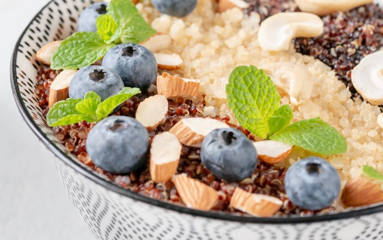 Bowl of cooked quinoa with nuts and blueberries